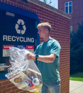 Henry Walke, an environmental and sustainability studies and economics junior, brings recyclable materials from his residence hall to a recycling compactor.