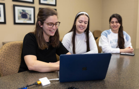 Diana Byrne with two students reviewing information on a laptop.